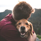 man cuddling his golden retriever